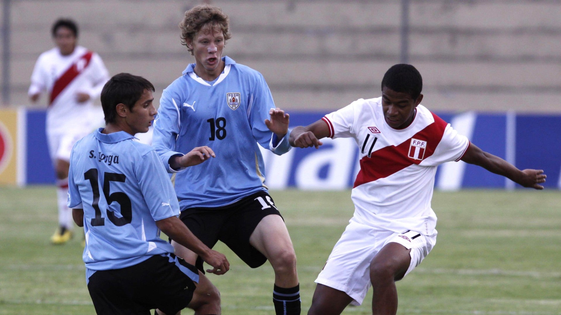 El jugador de Perú Andy Polo disputa el balón con los jugadores Sebastián Canobra y Sebastían Gorga de Uruguay | Foto: EFE