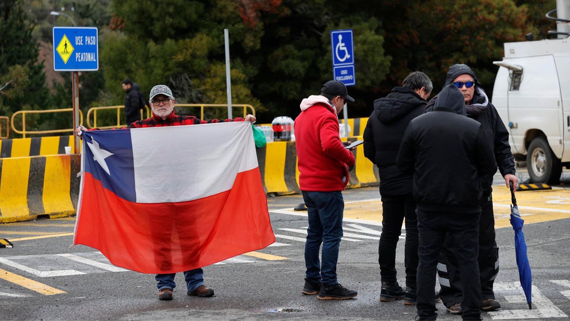 Un hombre sostiene bandera Chile en acceso Los Maitenes, en la mina El Teniente - Foto EFE Un hombre sostiene bandera Chile en acceso Los Maitenes, en la mina El Teniente - Foto EFE