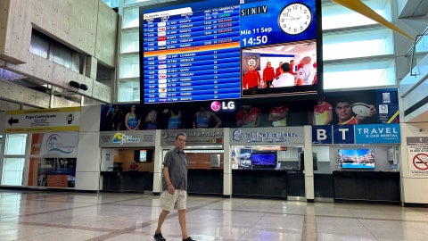 Un hombre camina frente a una pantalla con información de vuelos internacionales en el Aeropuerto Internacional de Maiquetía. (Foto de referencia - EFE)