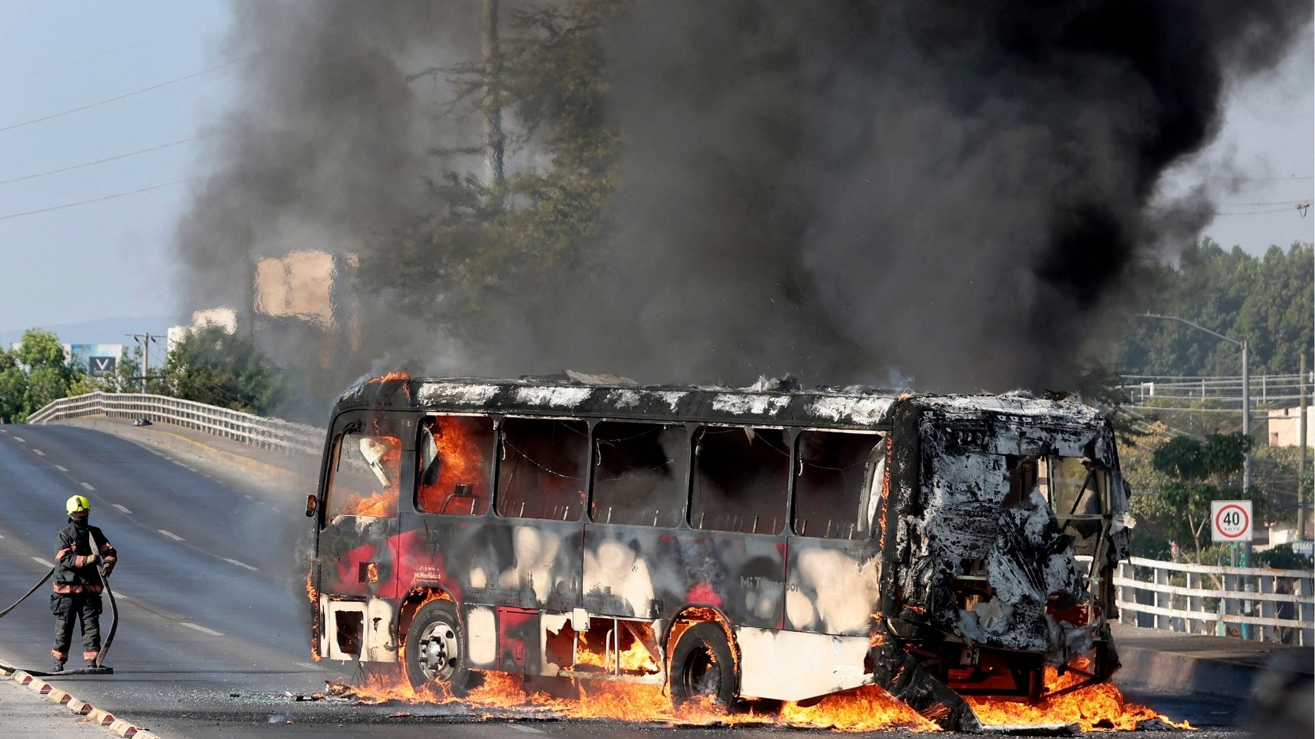 Un bombero extingue un autobús en llamas incendiado por grupos del crimen organizado en respuesta a un operativo en Jalisco-Foto: AFP