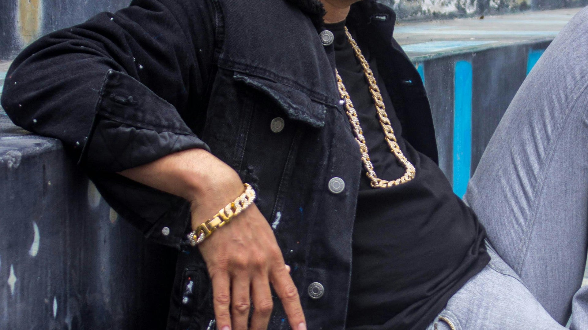 Hombre sentado portando una cadena y brazalete - Foto de referencia: Pexels