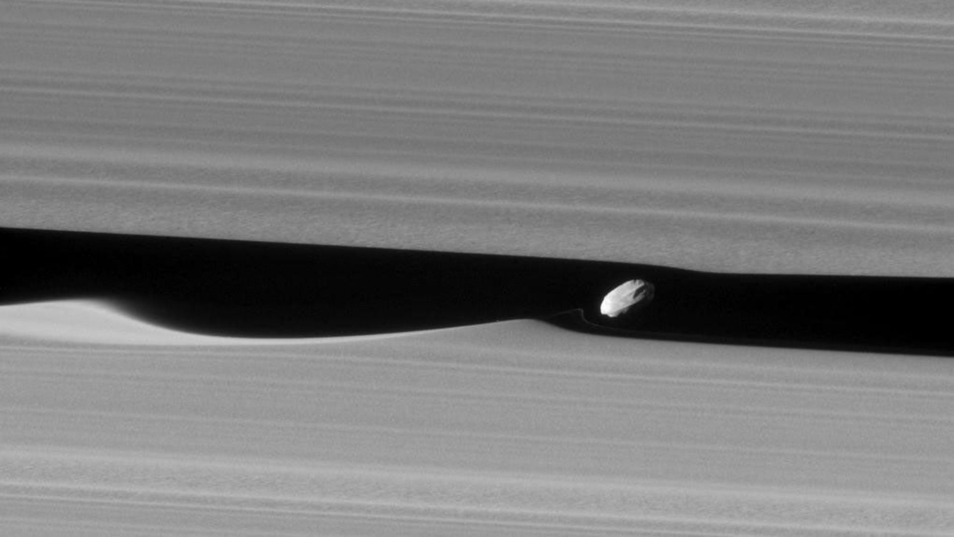 Imagen de Daphnis y el patrón de ondas generado en los anillos de Saturno - NASA
