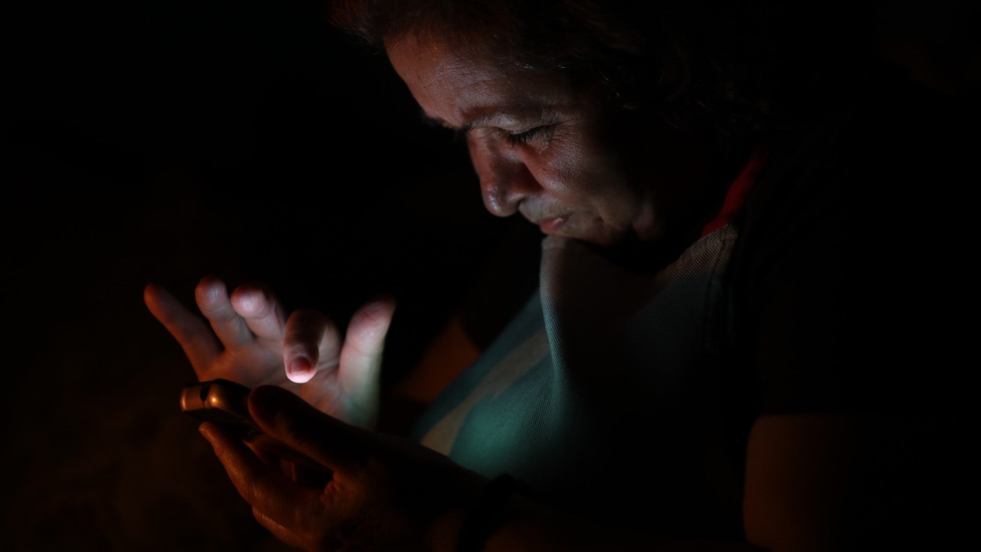 Una mujer observa a oscuras su teléfono en Caracas (Venezuela) - Foto de referencia: EFE