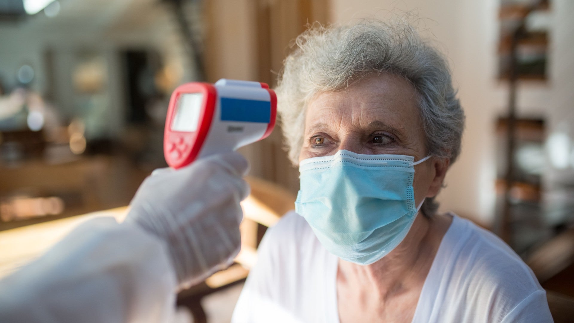 Una mujer mayor con mascarilla recibe un chequeo de temperatura con un termómetro infrarrojo - Foto de referencia: Pexels