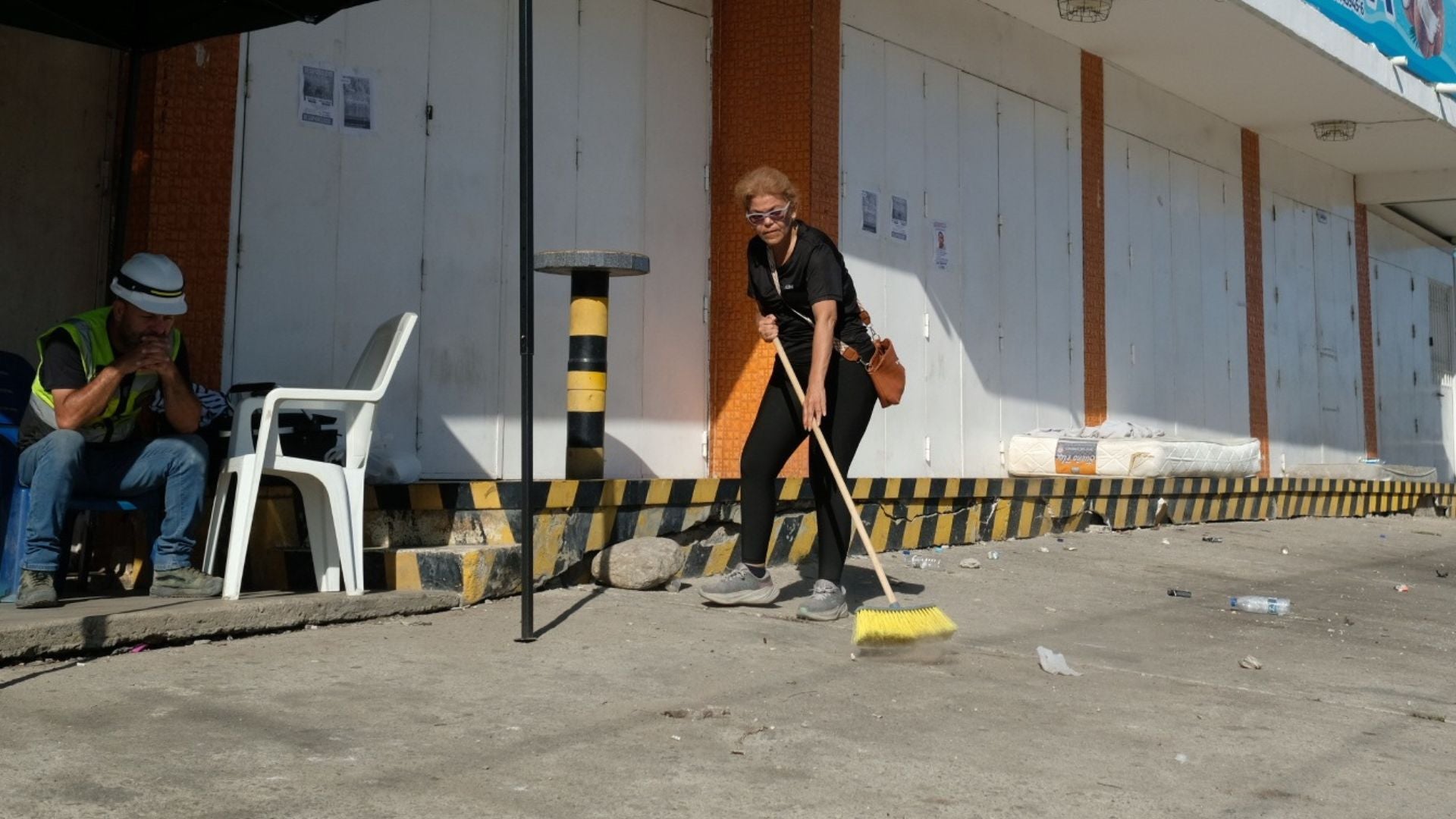 Una mujer limpia el exterior de locales comerciales cerrados en Macuto (La Guaira, Venezuela) - Foto de referencia: EFE