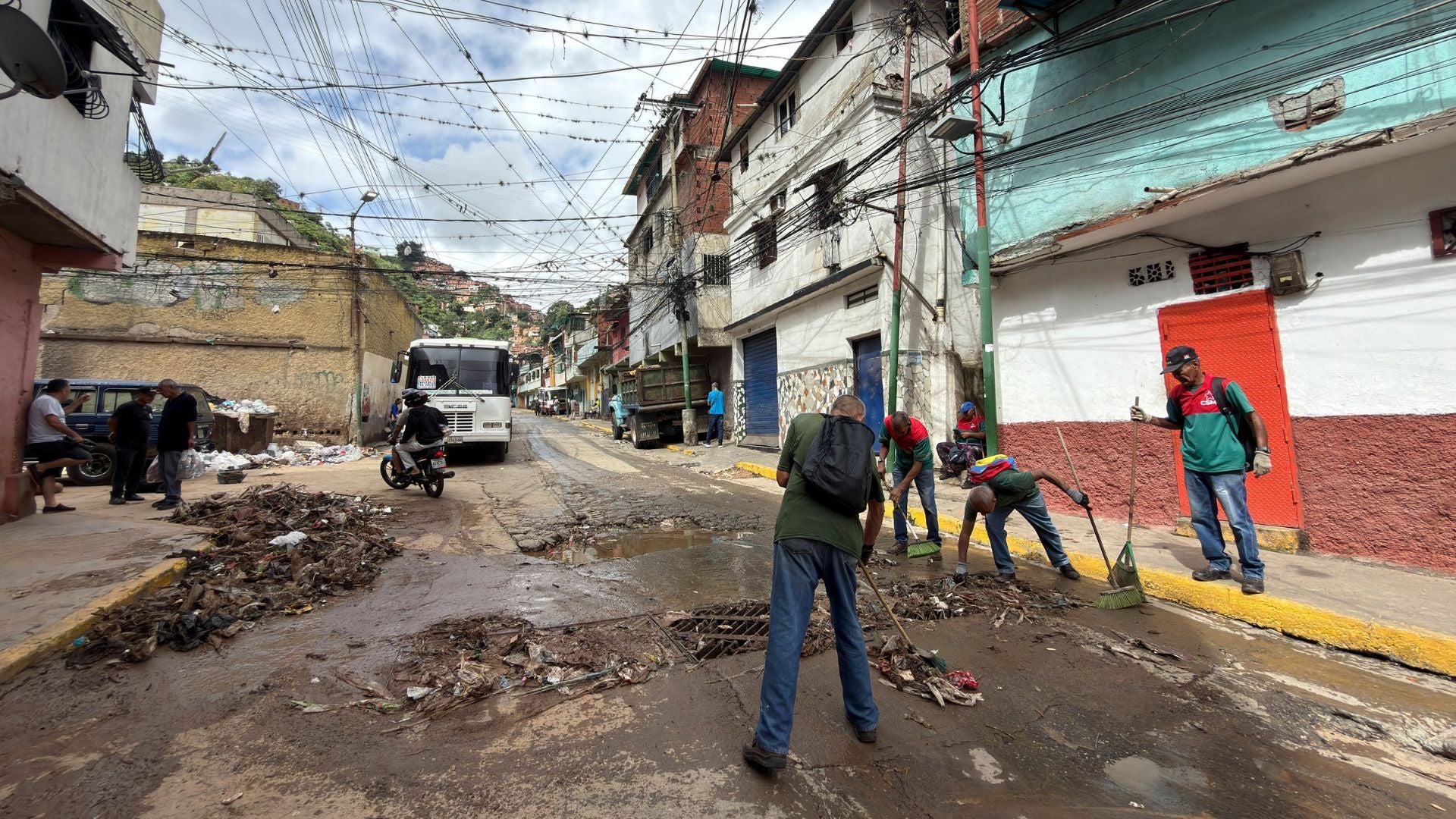 Personas limpian una calle tras las fuertes lluvias este domingo, en Caracas-Foto: EFE