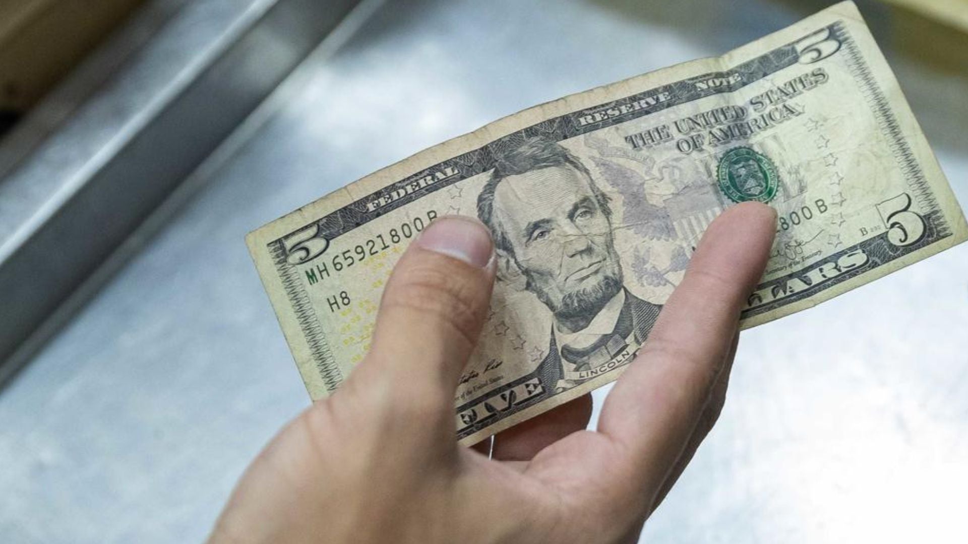 Hombre paga un producto en un local comercial de Venezuela con un billete de 5 dólares - Foto de referencia: EFE