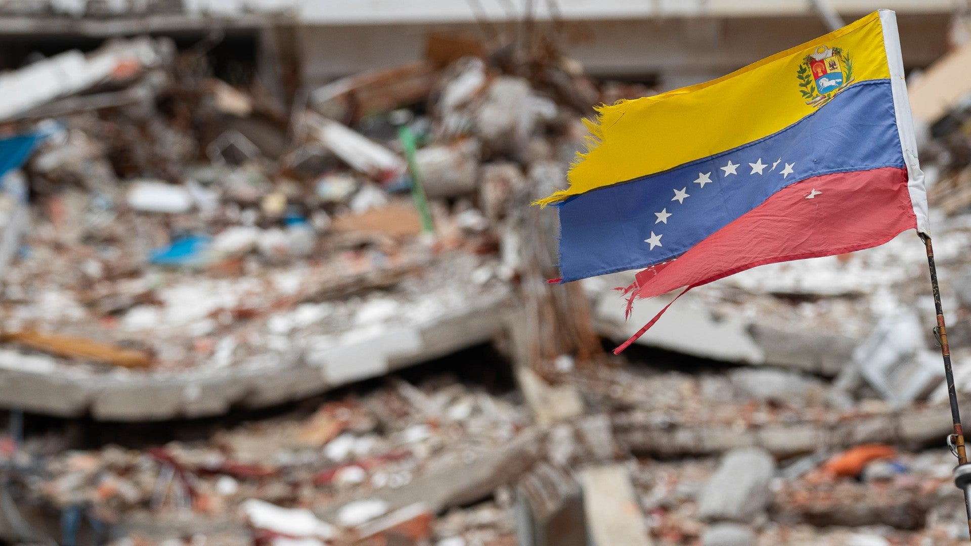 Fotografía de una bandera de Venezuela frente a un edificio colapsado por los terremotos del 24 de junio de 2026 en La Guaira (Venezuela) - EFE