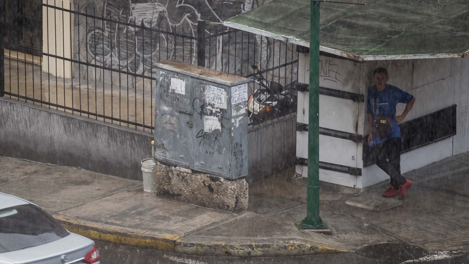 Un hombre esperando que pase un aguacero en Caracas (Venezuela) - Foto de referencia: EFE