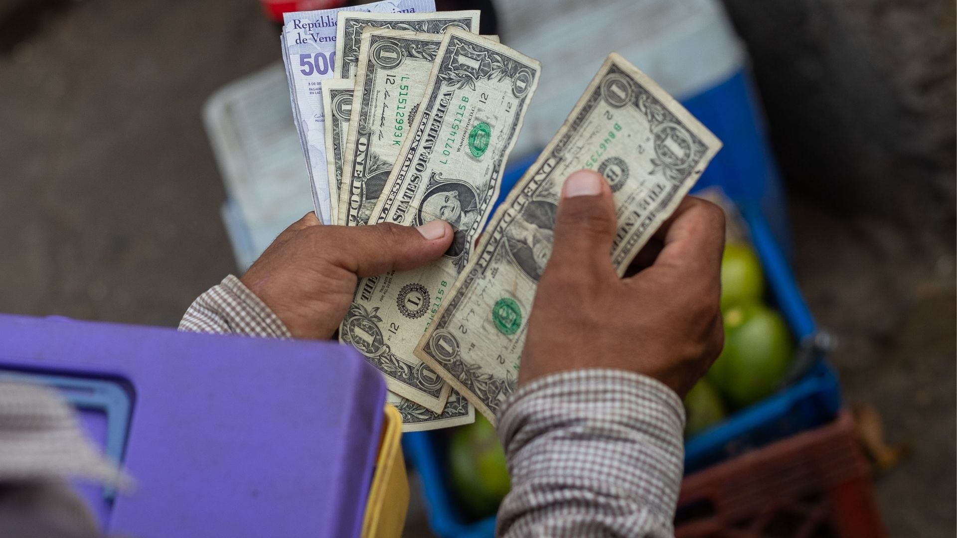 Un vendedor ambulante cuenta sus ganancias en dólares y bolívares en Venezuela - Foto de referencia: EFE