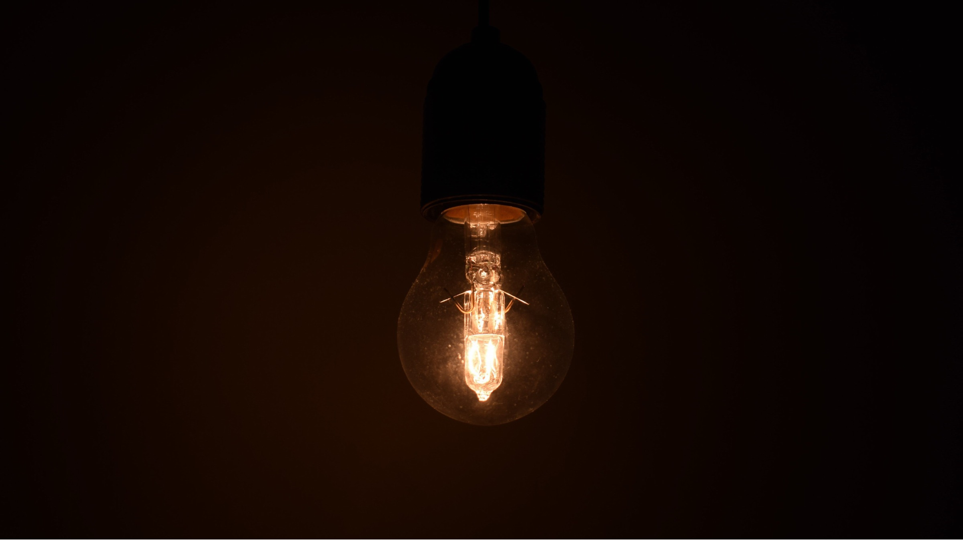 Vista en primer plano de un bombillo iluminado brillando en un entorno oscuro - Foto de referencia: Pexels